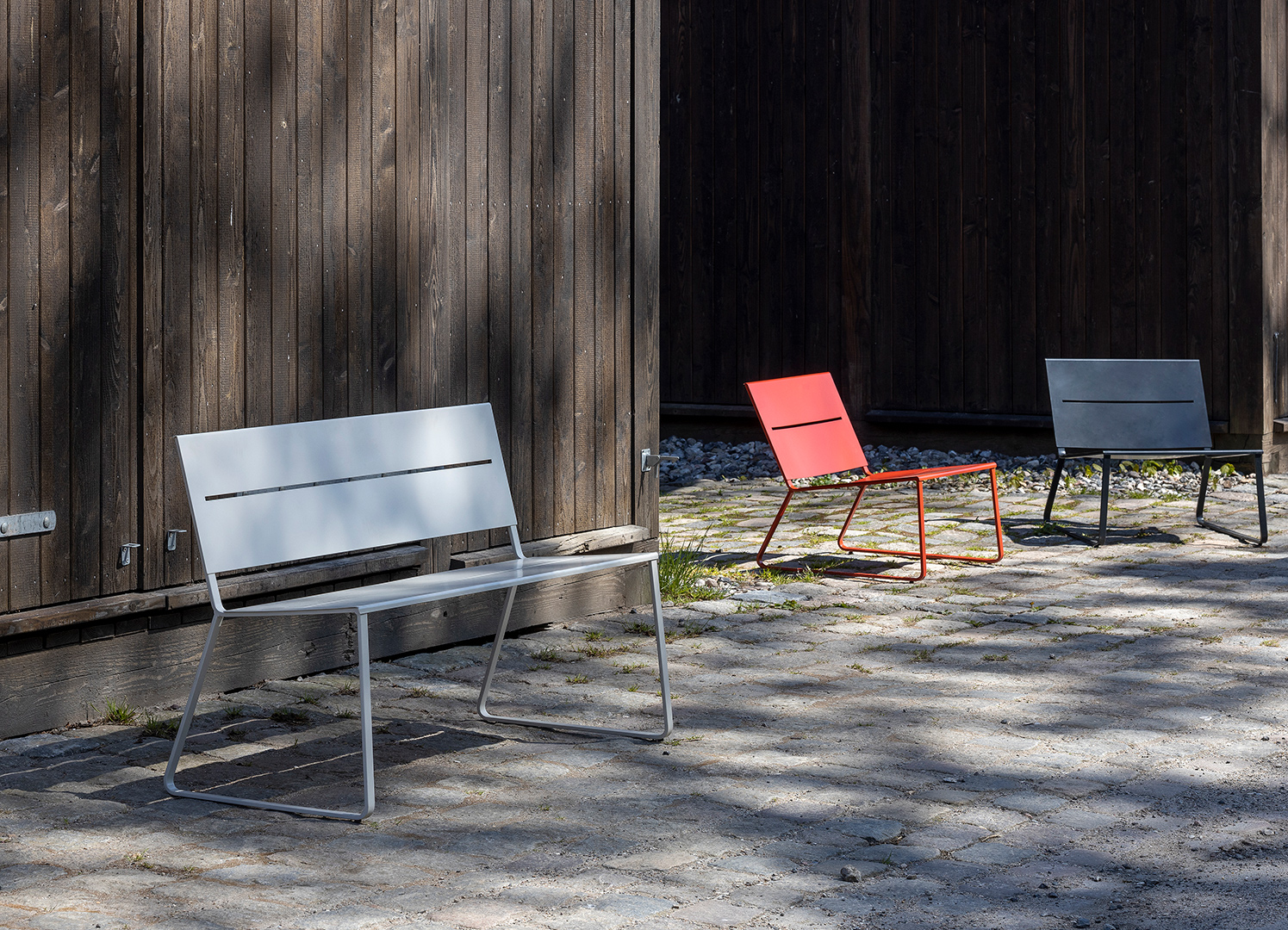 White TERÄS park bench in front of two lounge chairs