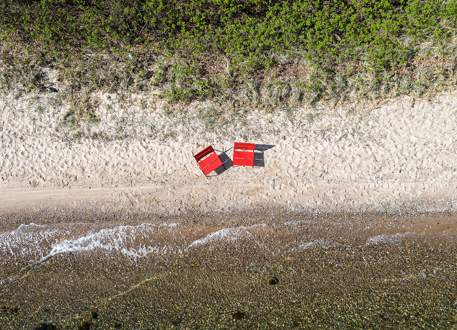 Two red TERÄS lounge chairs on the beach