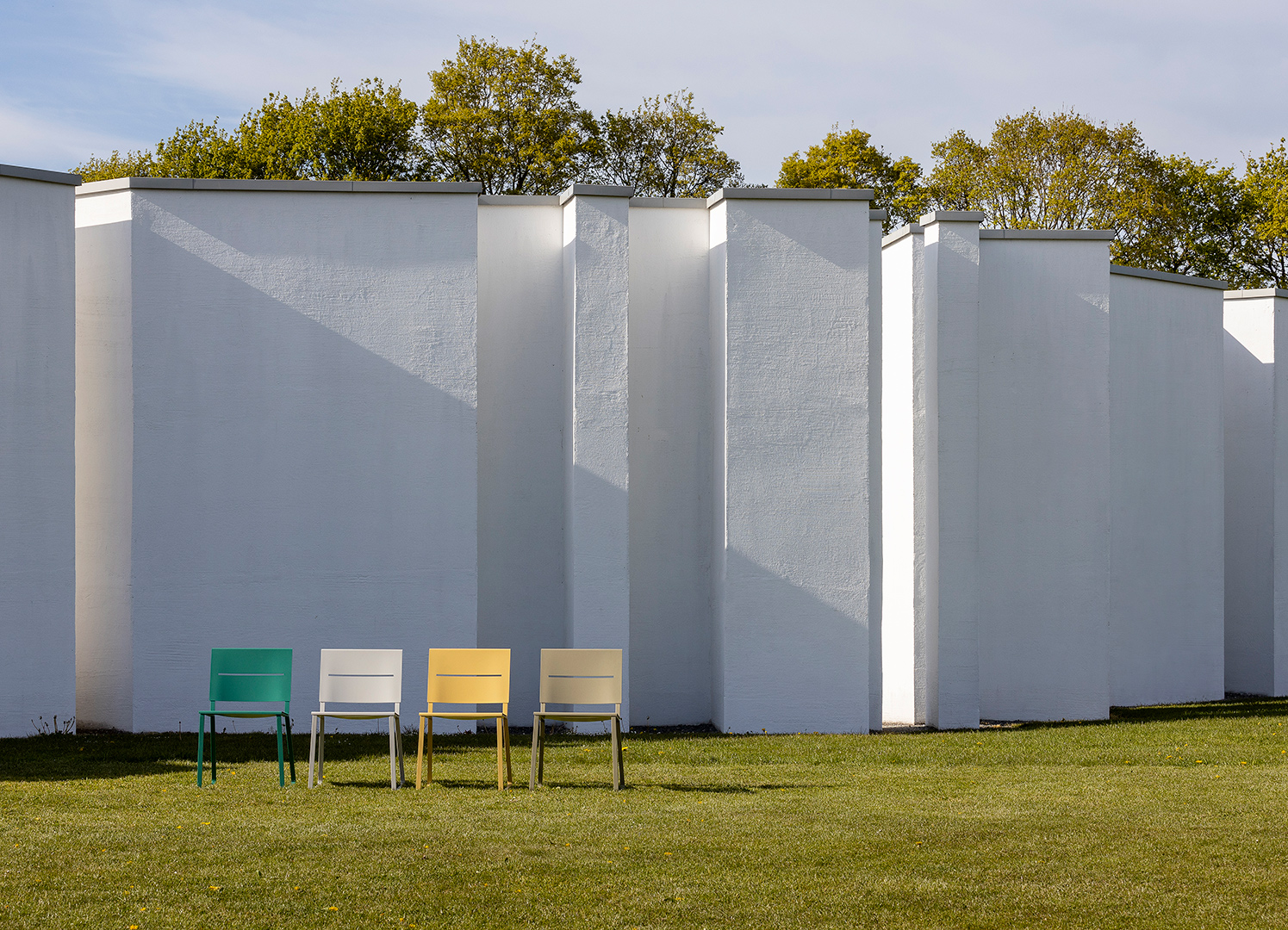 Steel chairs on a lawn in front of a white wall